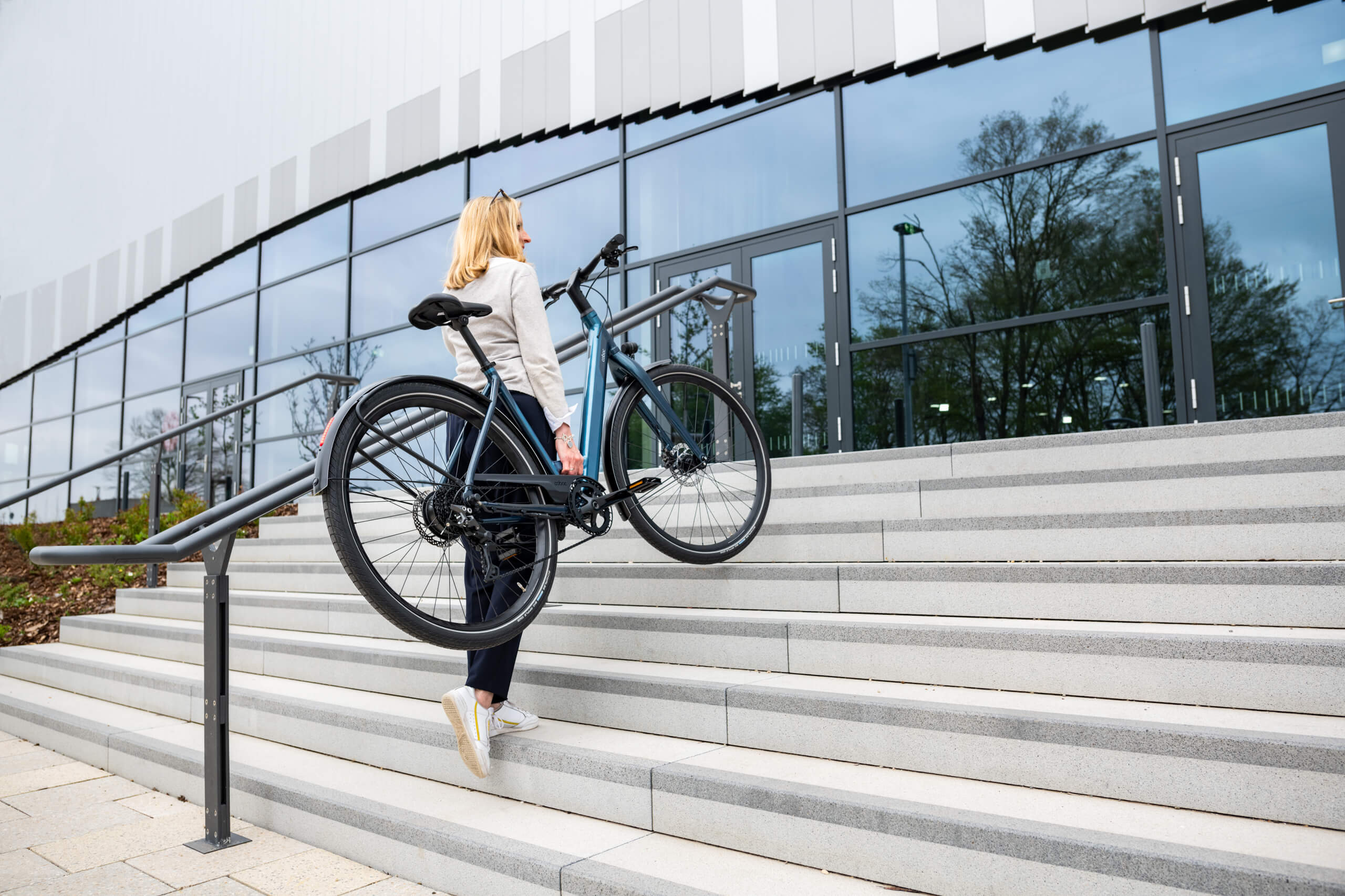 Frau trägt E-Bike Kallio RGD die Treppe hoch