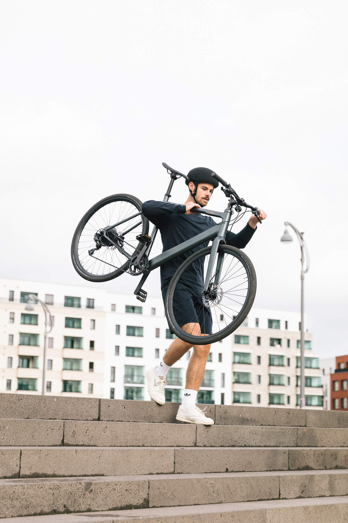 Mann trägt urbanes, sportliches E-Bike Coboc Sydney über Treppe