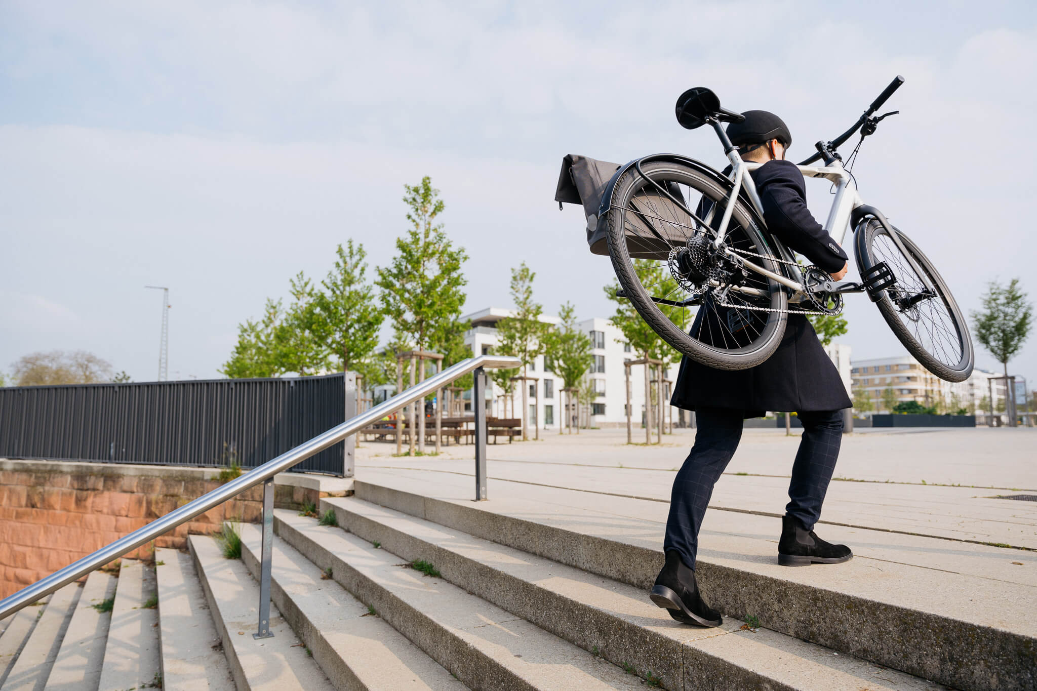 Mann trägt E-Bike Coboc Vesterbro DMT Raw dei Treppe hoch