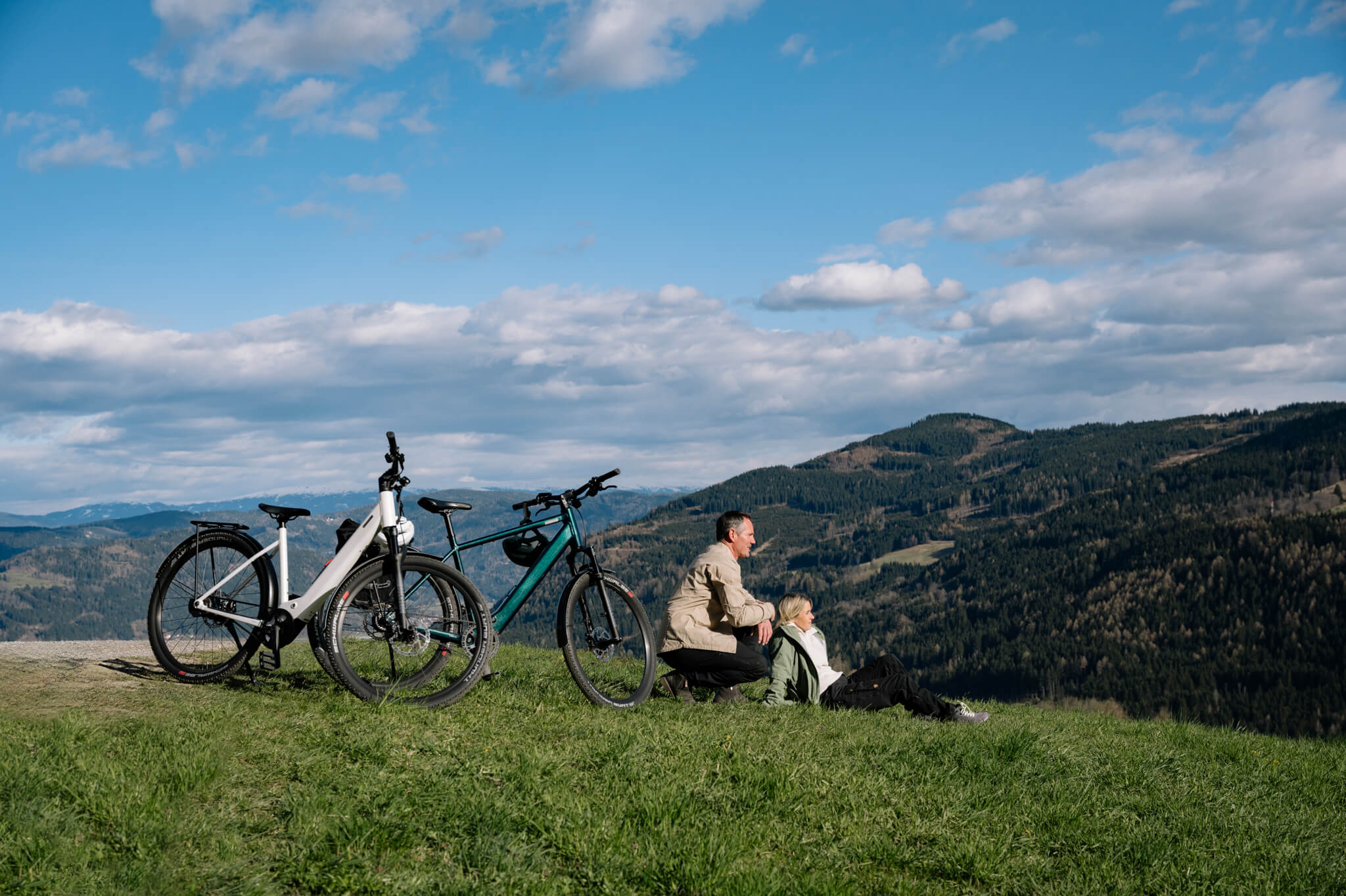 Mann und Frau sitzen neben Coboc E-Bikes Skye Belt auf Wiese